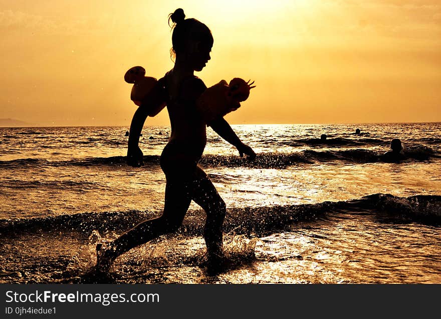 Silhouette of Girl Running on the Seashore during Golden Hour