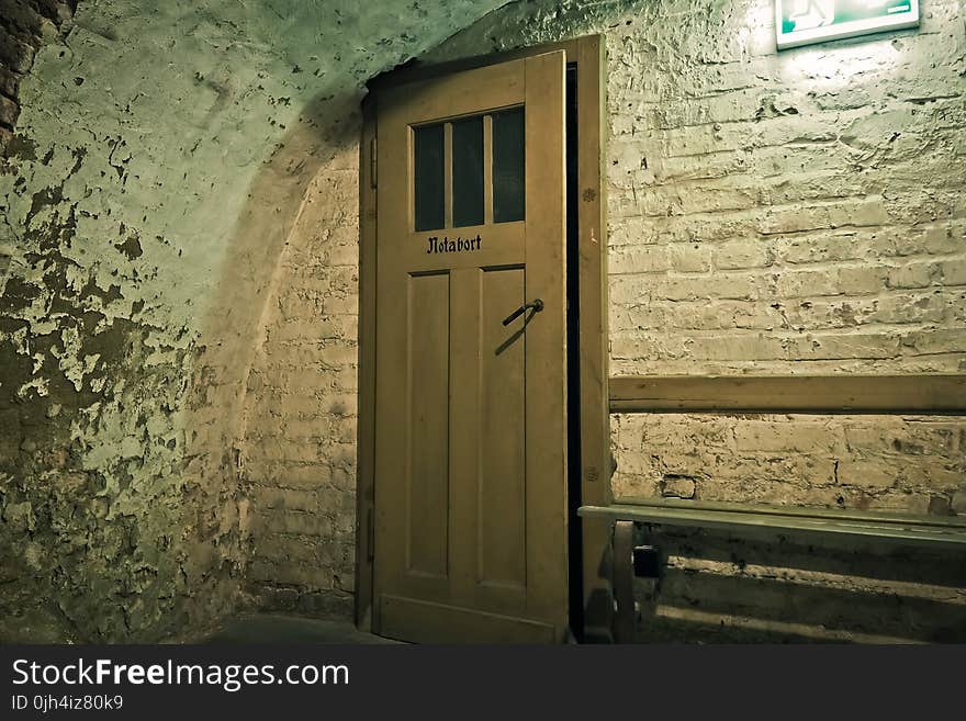 Brown Wooden Door Near White Brick Wall