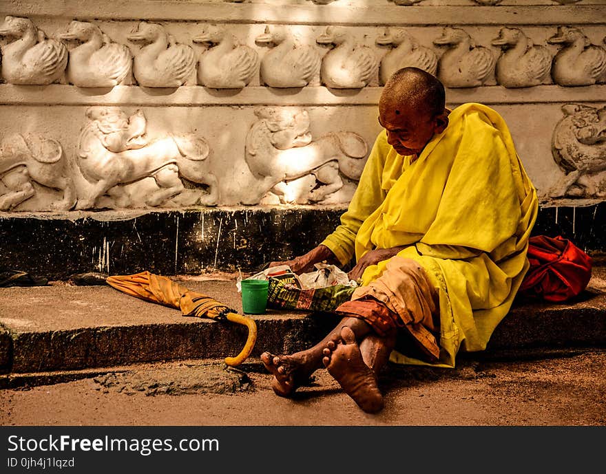 Man in Yellow Sitting Outside during Daytime