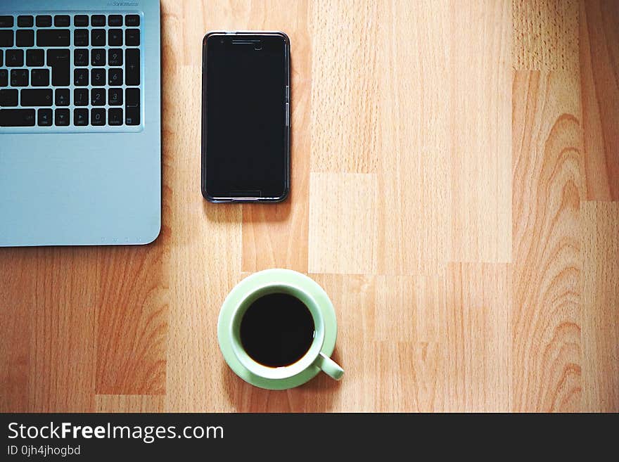 White Ceramic Mug Near Black Smartphone