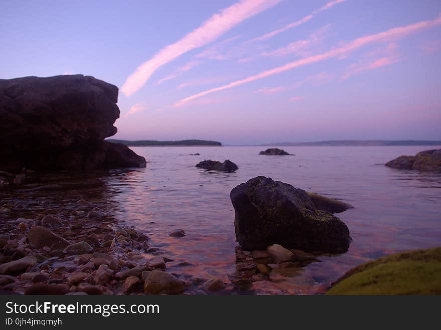 Rock Formation on Body of Water Under Altostratus Clouds