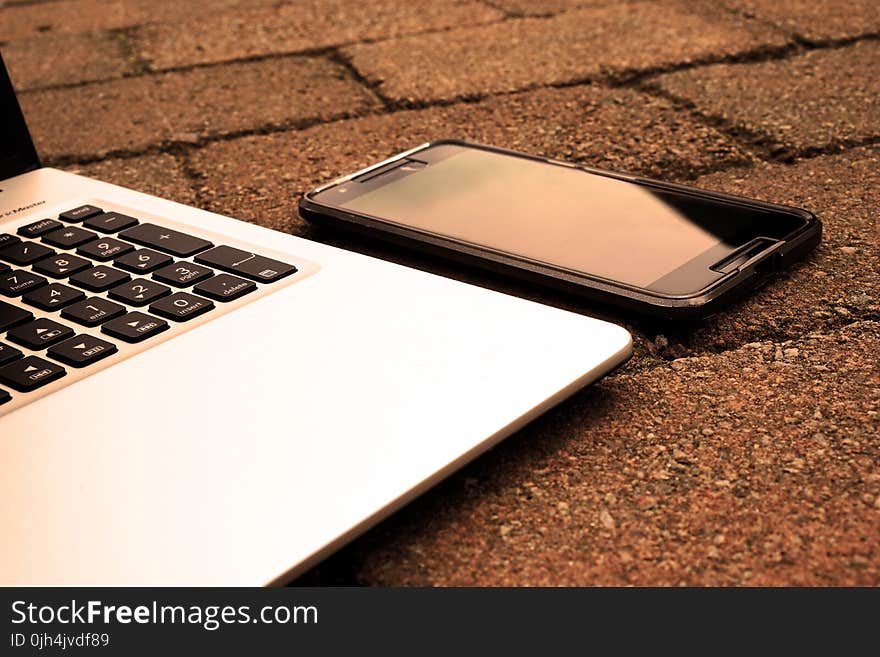 Silver Laptop Computer Beside Black Android Smartphone Turned Off