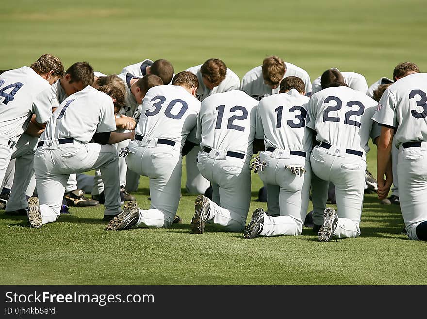 Baseball Player Kneeling on Grass Field during Daytime