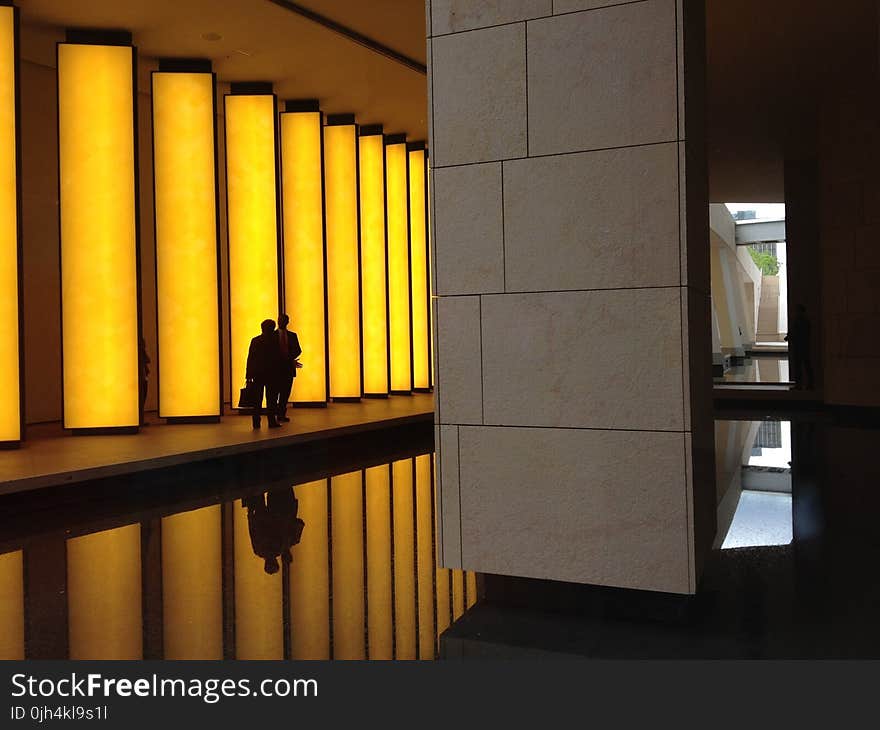 Silhouette Photo of 2 Person Beside Beige Concrete Lighted Wall