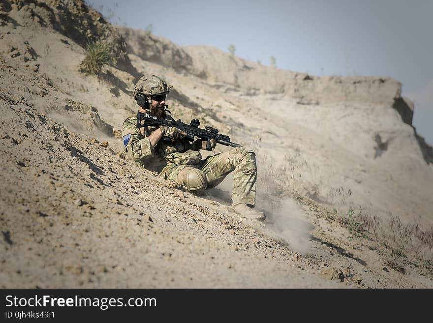 Soldier Man With Black Rifle Sliding on Cliff