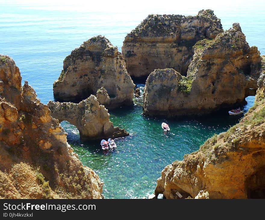 3 White Boats Near a Rock Formation