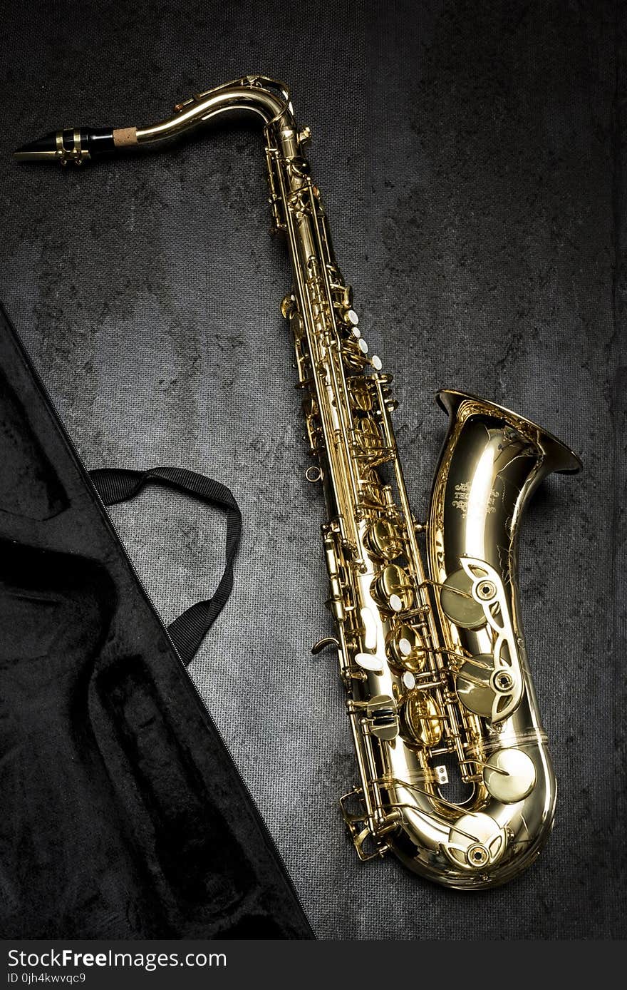 Brass Saxophone on Gray Table Near Black Bag