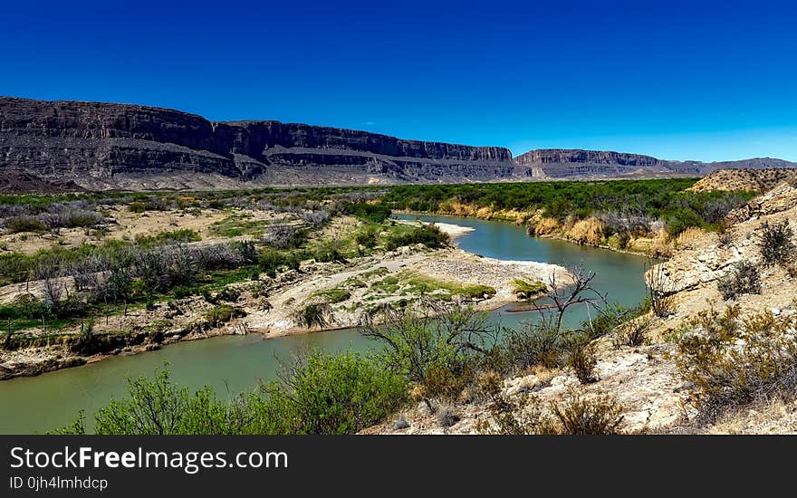 Body of Water Between 2 Mountains Under Clear Sky during Daytime