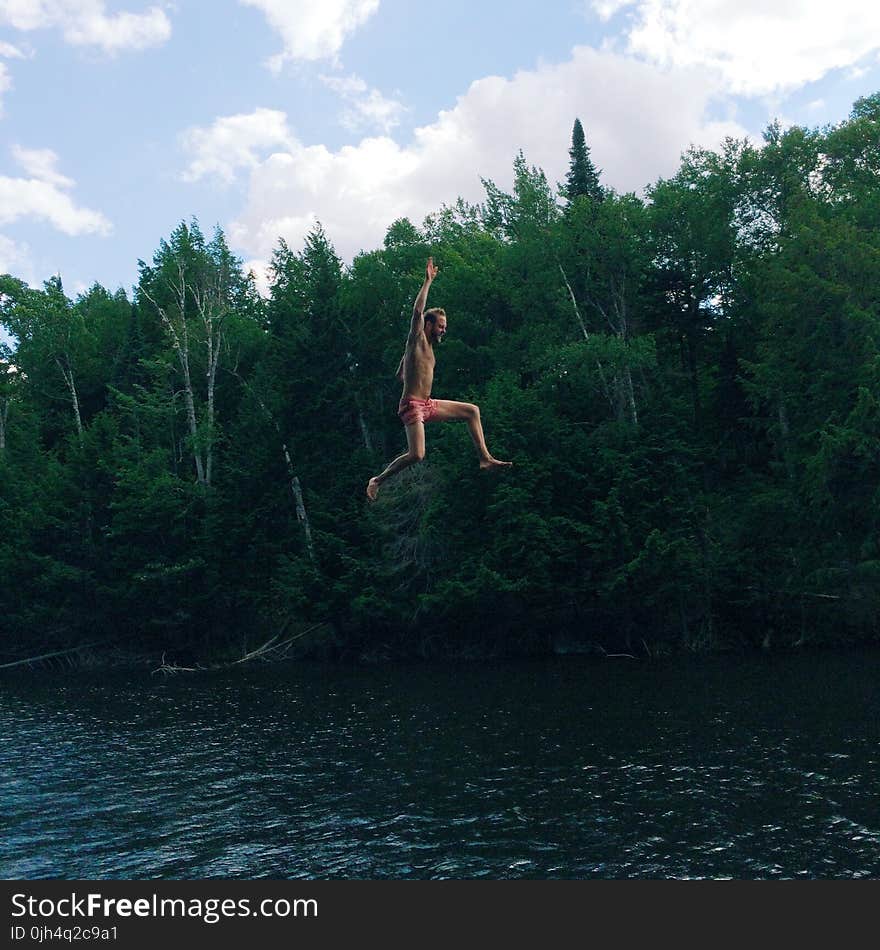 Man in Pink Shorts Jumping on Body of Water