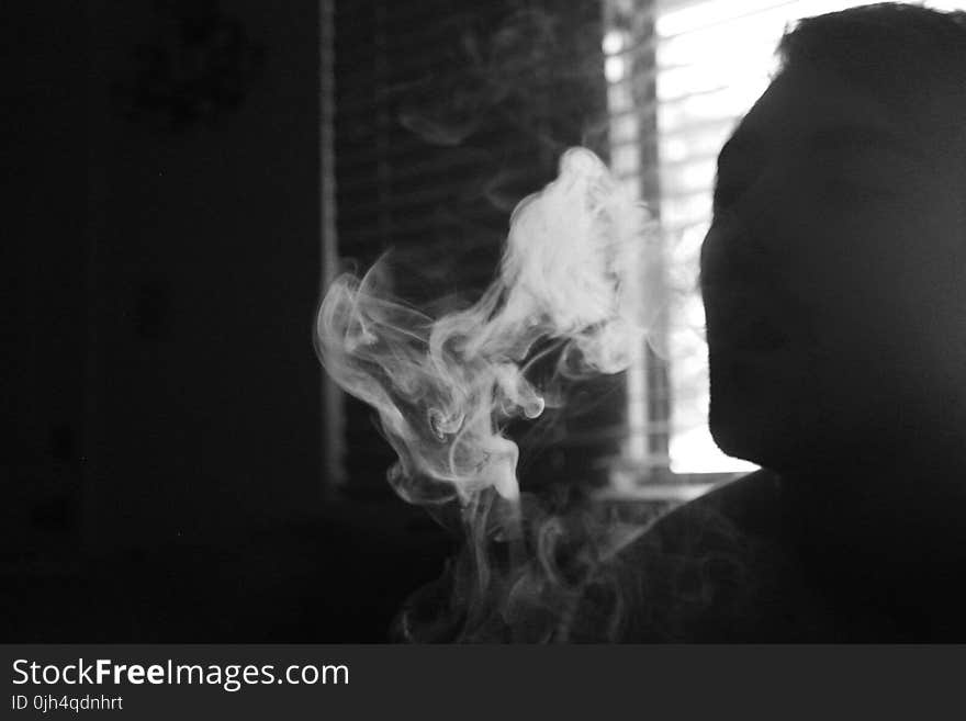 Gray Scale Photo of Human Smoking Inside the Room