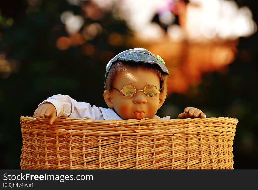 Baby Doll Wearing Eye Glasses Inside the Brown Wicker Basket