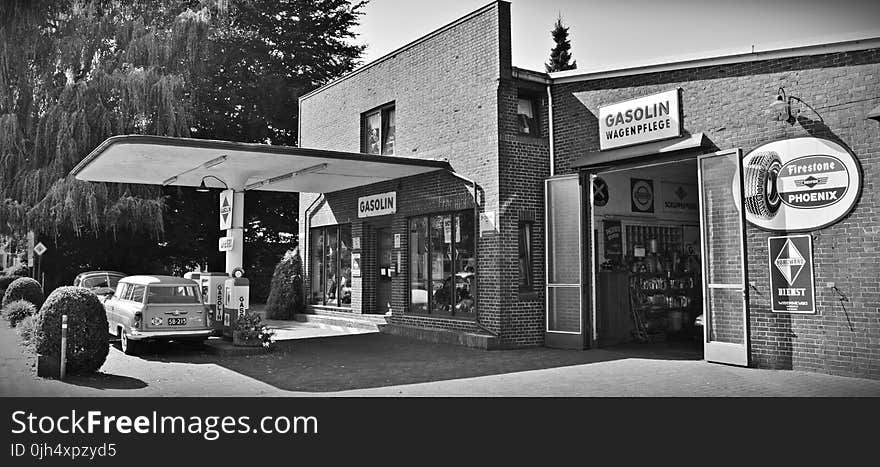 Gray Scale Photo of a Sedan Parked Infront of Store