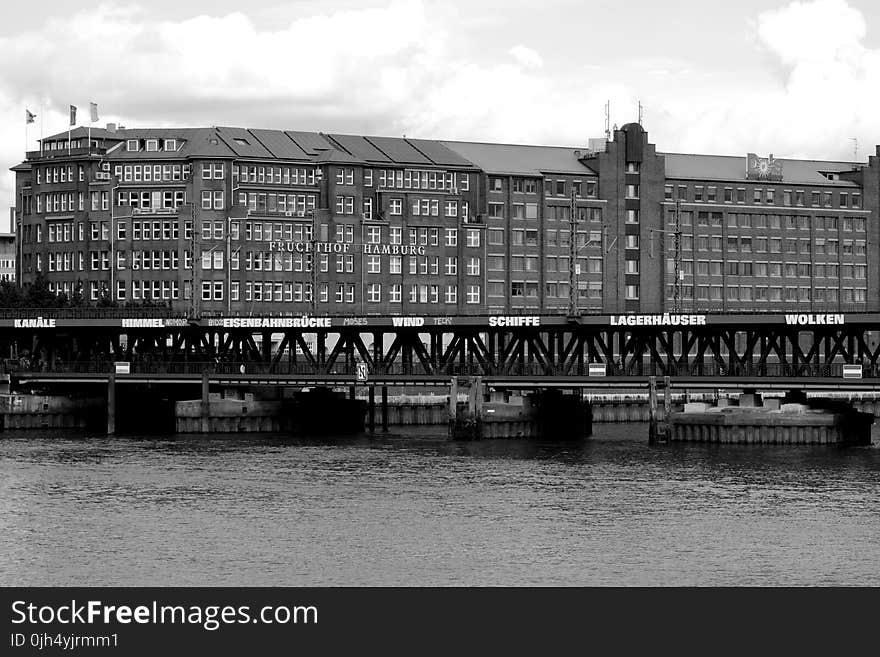 Grayscale Photo of Mid Rise Building Near Body of Water at Daytime