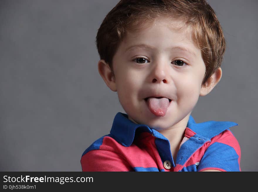 Child Wearing Blue and Red Stripes Polo Shirt Sticking Out Tongue