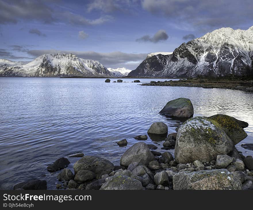 Black and Gray Rock Formations Beside Blue Body of Water