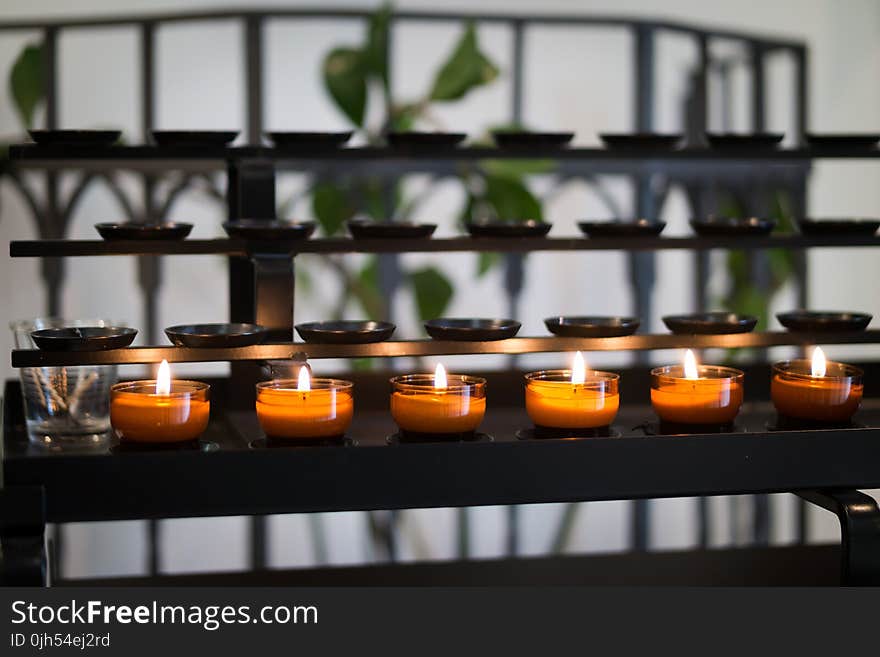 Close Up Photography of Tealight Candles on Black Metal Rack