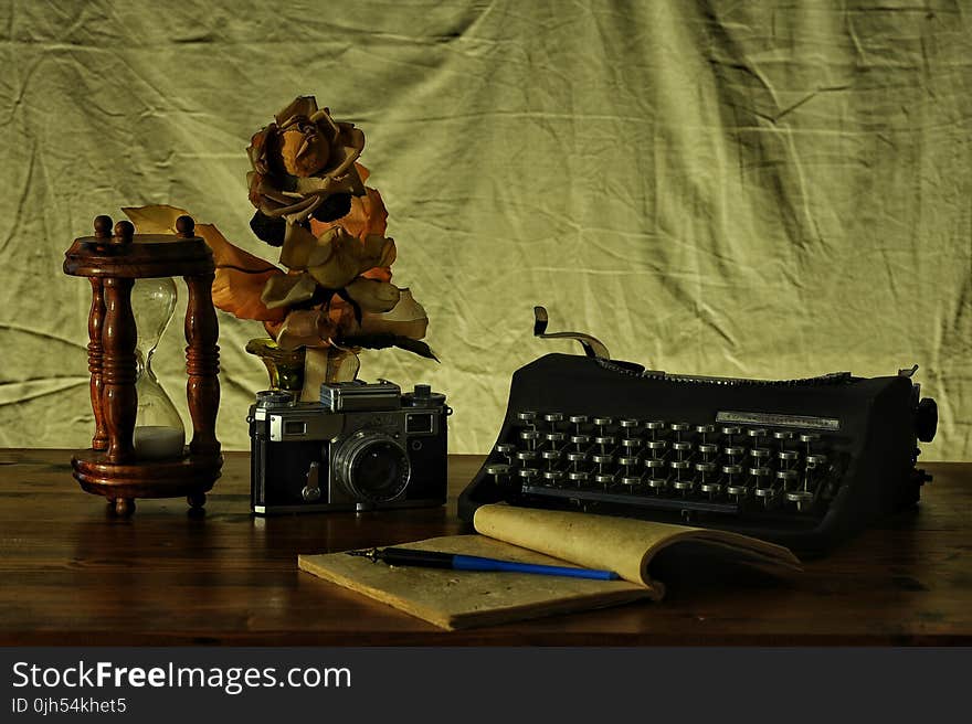 Brown Notebook in Between of a Type Writer and Gray and Black Camera