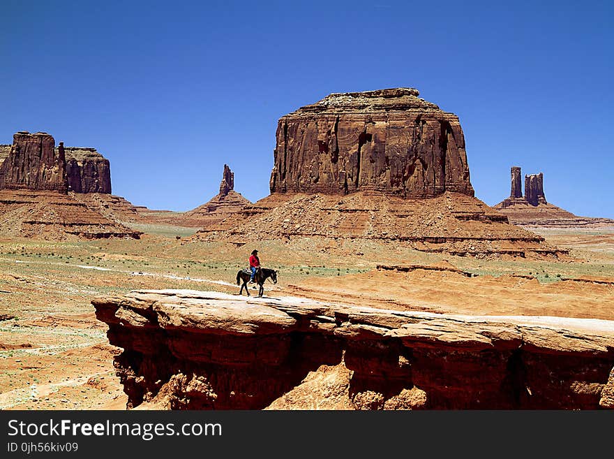 Person on Black Horse on Rock Cliff