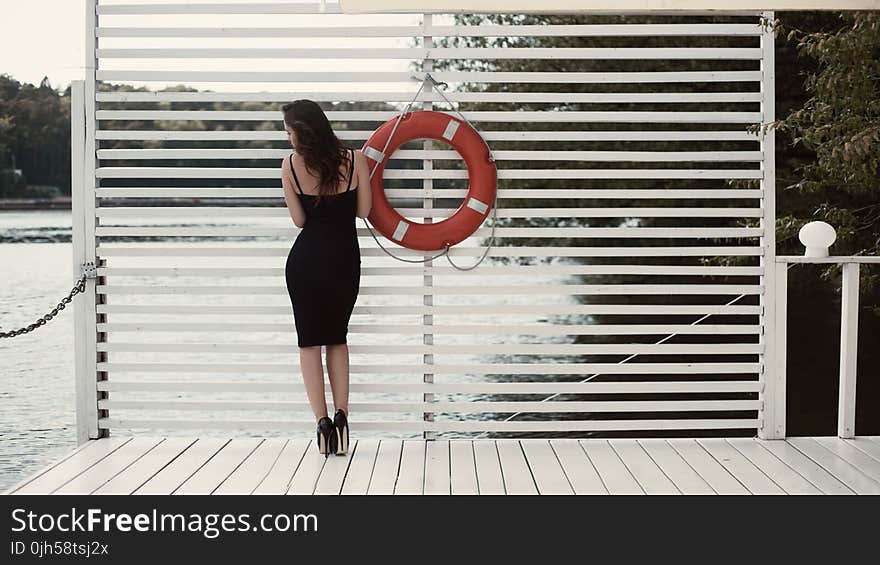 Woman in Black Sheath Dress Beside Swim Ring on Dock