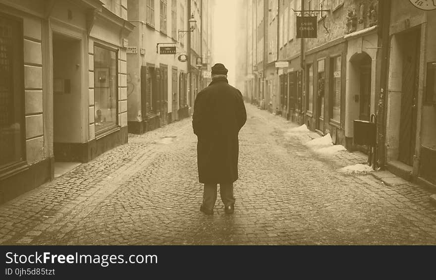 Rear View of a Man Walking on Cobblestone