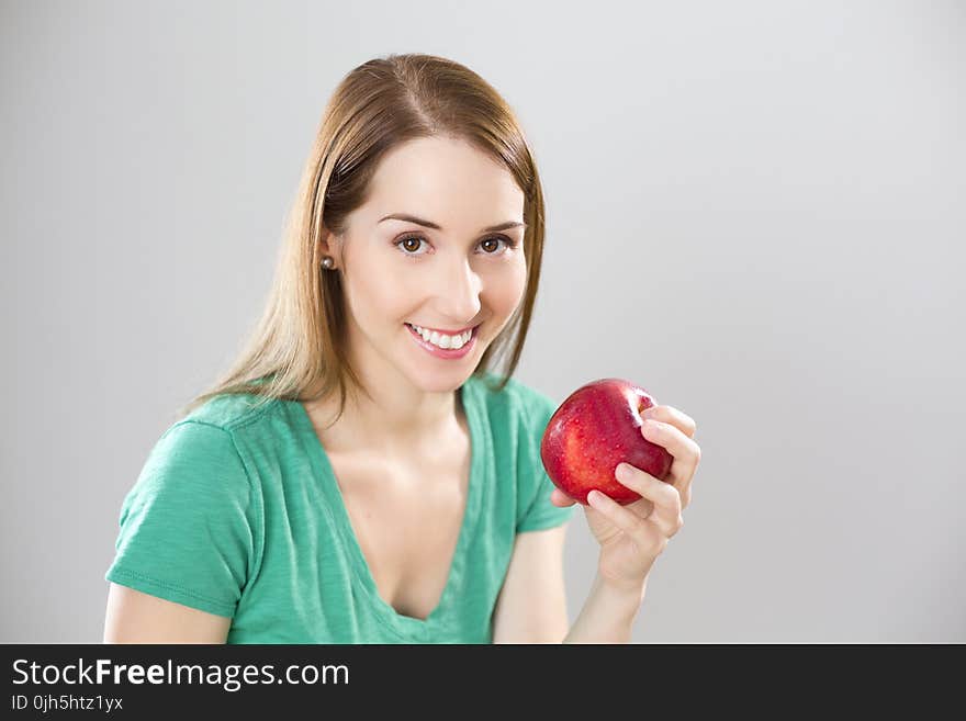 Portrait of Young Woman Eating Fruit Against White Background