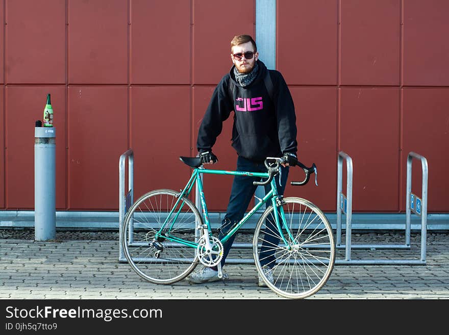 Person In Black Hoodie Holding Green Bike