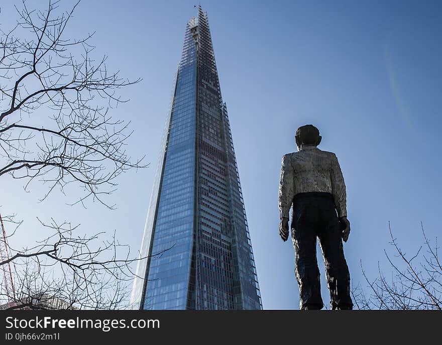 Man Standing in Front of a Sunrise Building Under Blue Sky