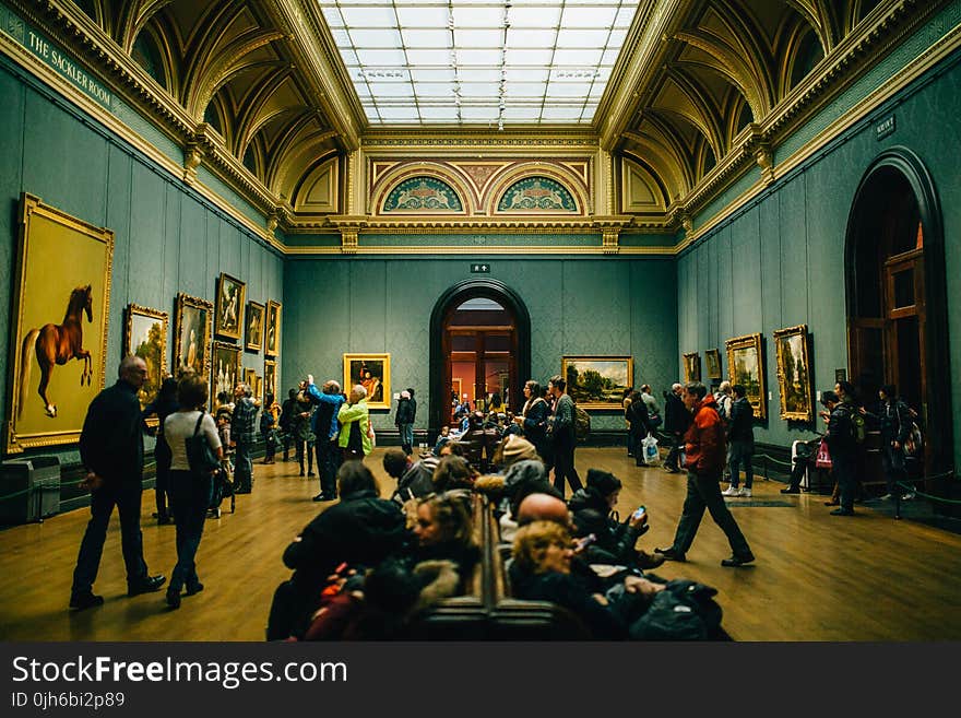 People Walking on Wooden Floor Inside Green Walled Building