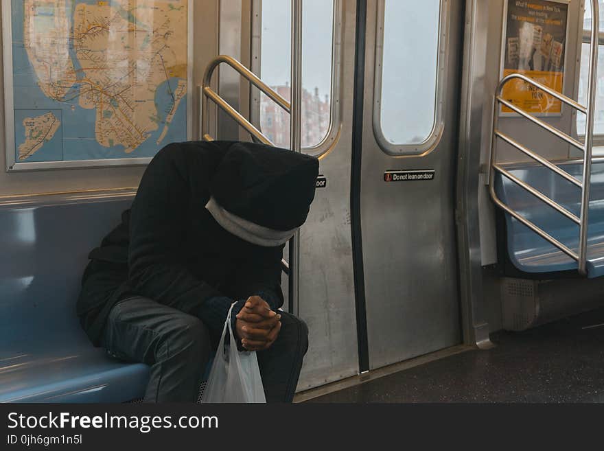 Person in Black Hoodie Sitting on Train Bench