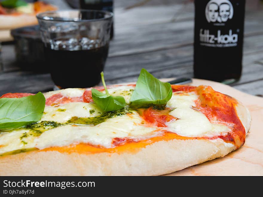 Pizza Top With Green Leafy Vegetable Near Glass of Black Liquid