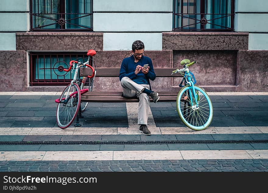 Person Sitting on Bench Between Two Road Bikes