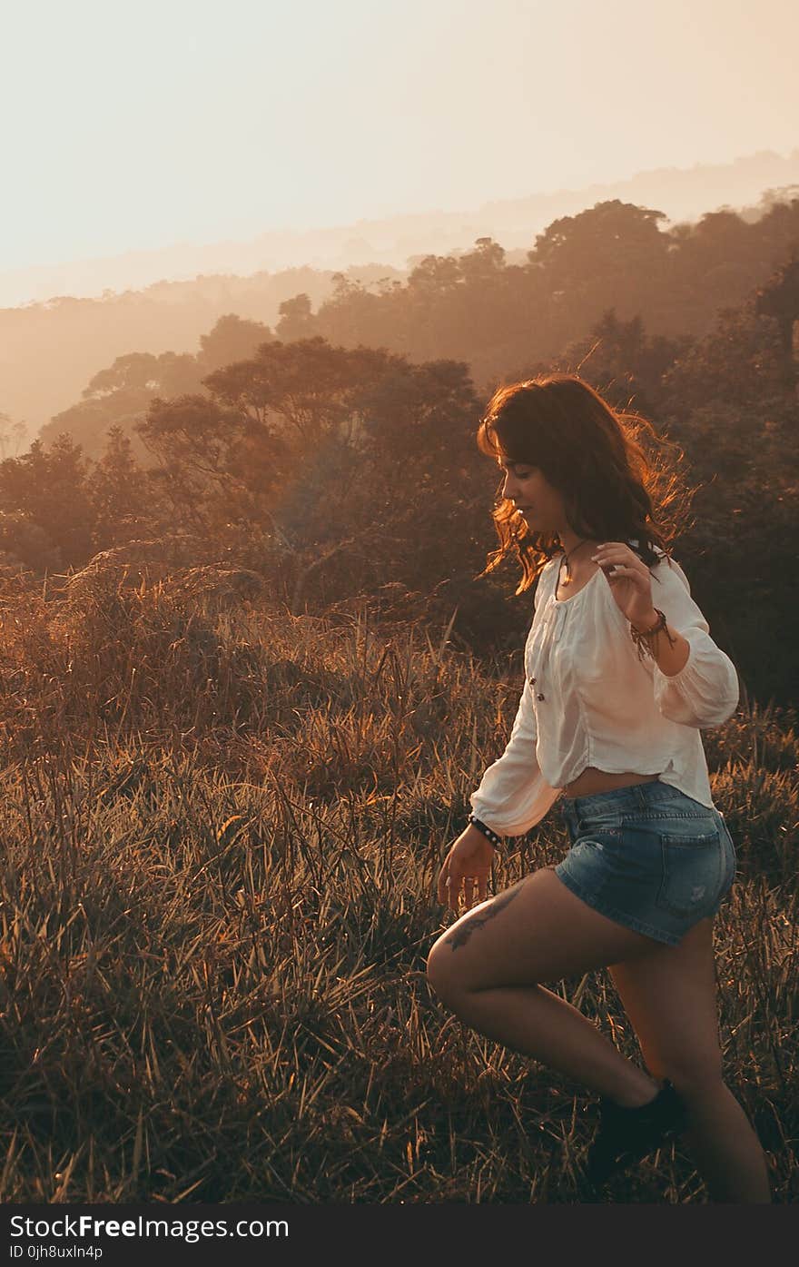 Women Wearing White Long-sleeved Blouse With Blue Denim Short Shorts Taken during Sunset