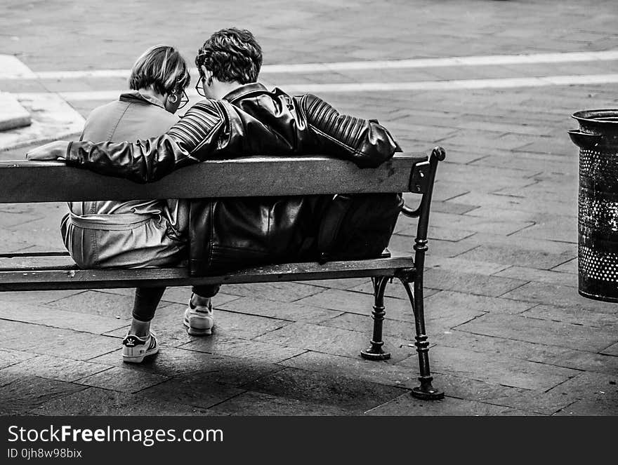 Grayscale Photo of Two Person Sitting on a Bench