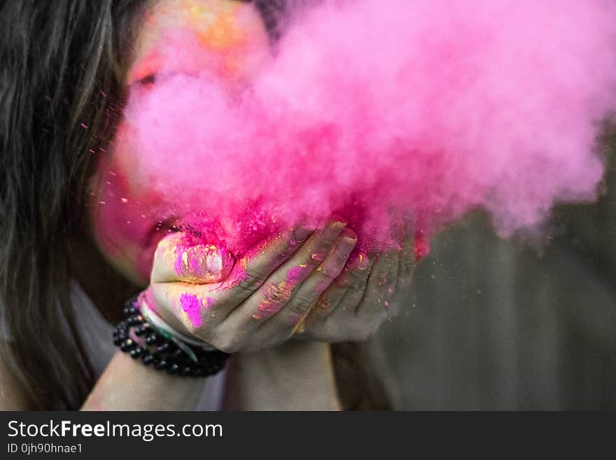 Shallow Focus Photograph of Woman Blowing Pink Powder