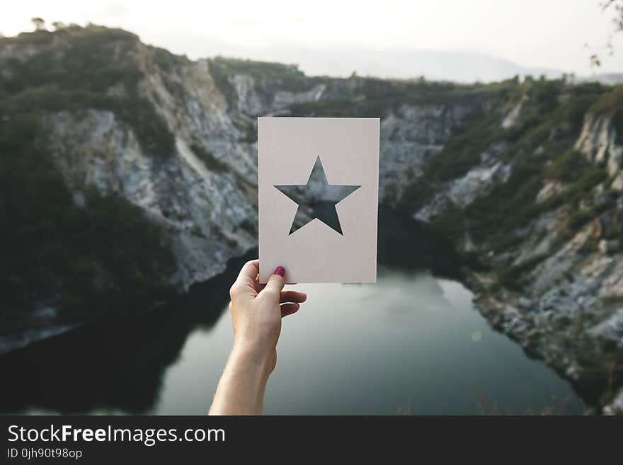 Person Holding Star Cutout Paper Facing Mountain