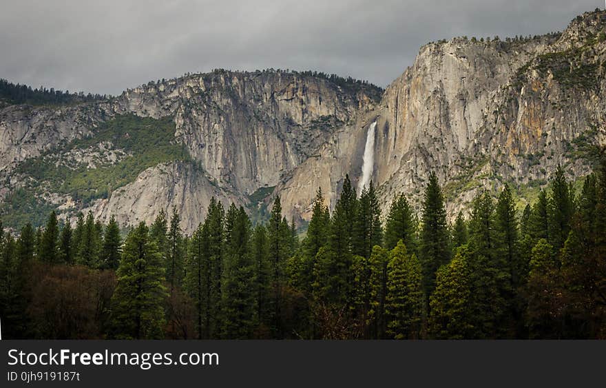 White Waterfalls Between Rocky Mountain during Cloudy Day