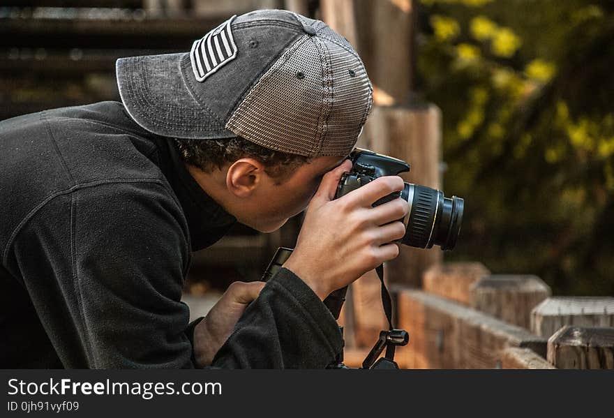 Depth of Field Photography of Man Holding Dslr Camera