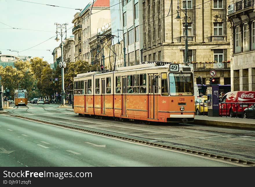 White and Orange Train Near City Buildings