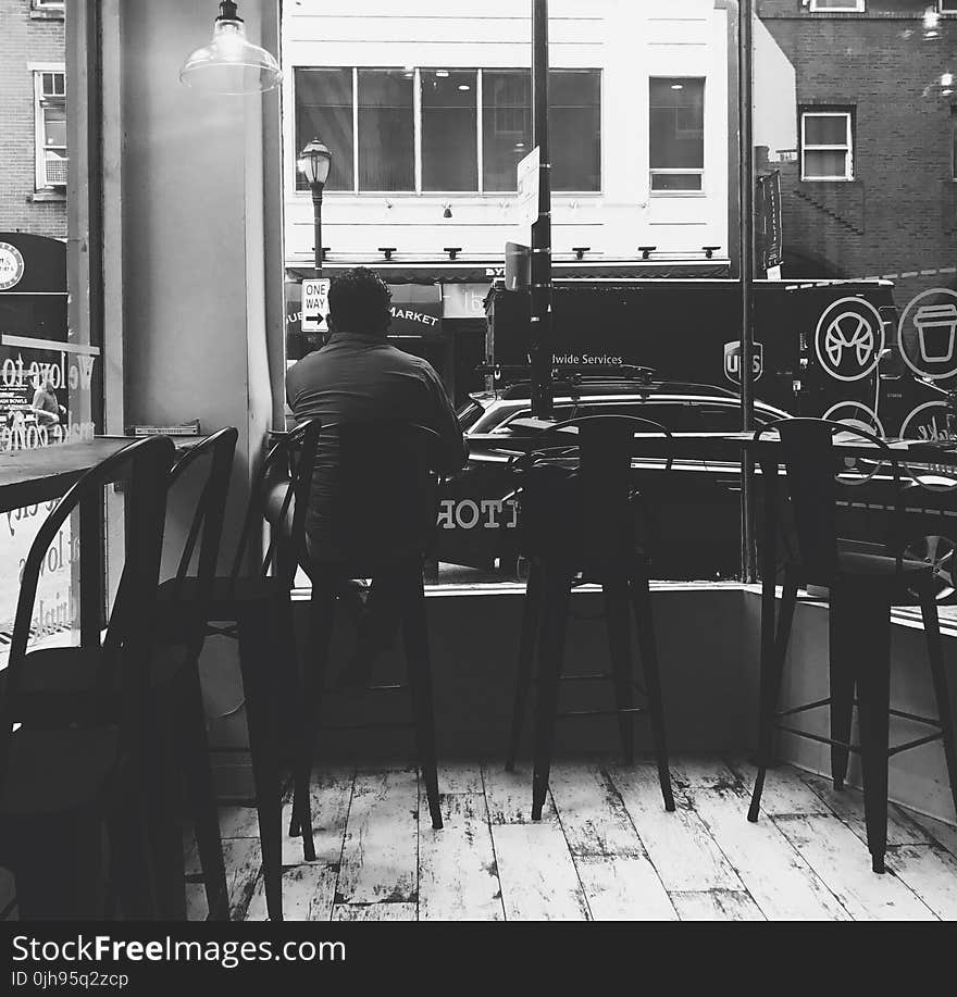 Monochrome Photography of a Man Sitting on the Chair