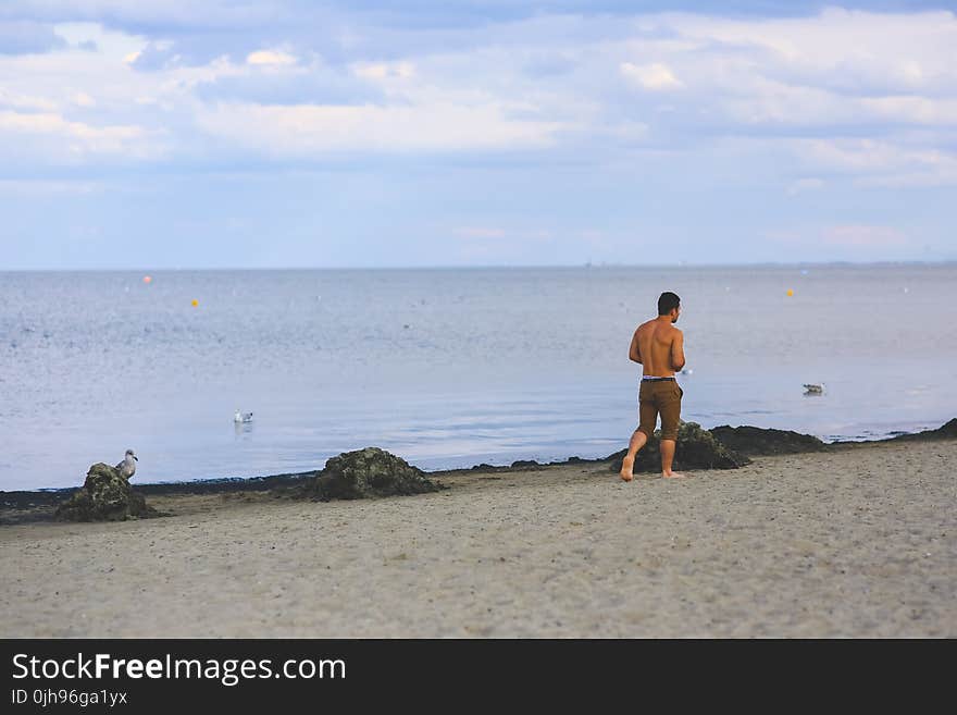 Young man walking on sand beach