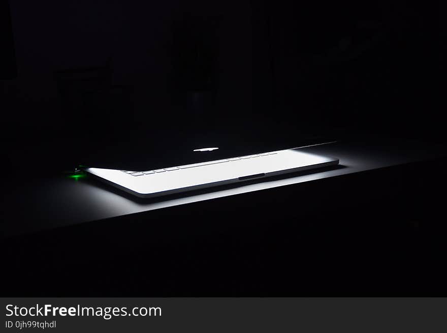 Photography of Macbook Half Opened on White Wooden Surface