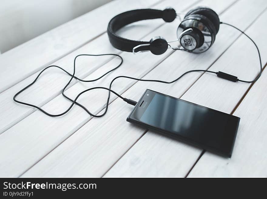 Black smartphone and headphones on a desk