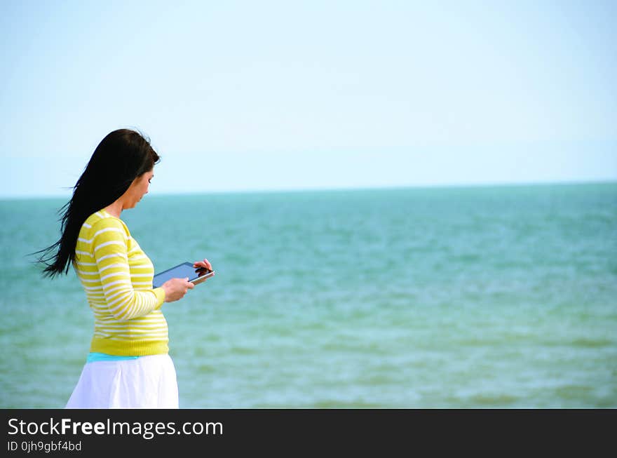 Woman In Yellow Long Sleeved Shirt And White Skirt Walking On Seashore