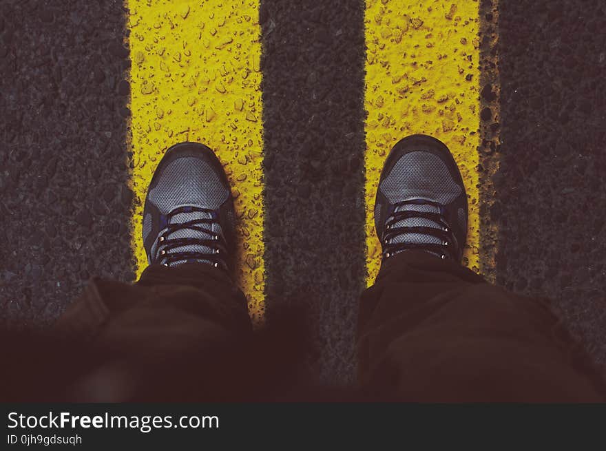 Person in Gray Sneakers Standing on Pedestrian Lane