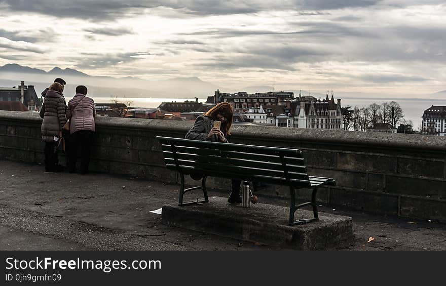 Woman Taking Photo While Sitting on the Bench Behind the Building Scenery