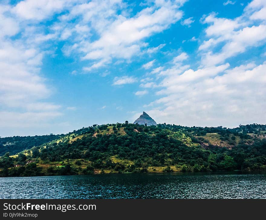 Mountain Surrounded by Green Trees in Front of Body of Water Photo