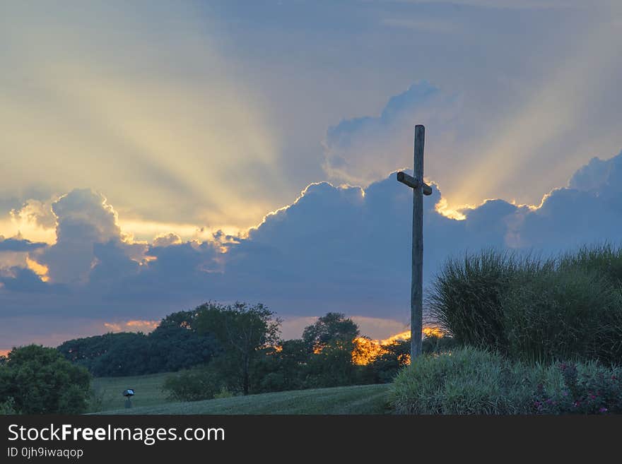 Big Wooden Cross On Green Grass Field Under The White Clouds