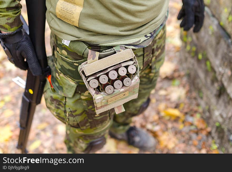 Person in Green Camouflage Print Pants Carrying Shotgun Shells