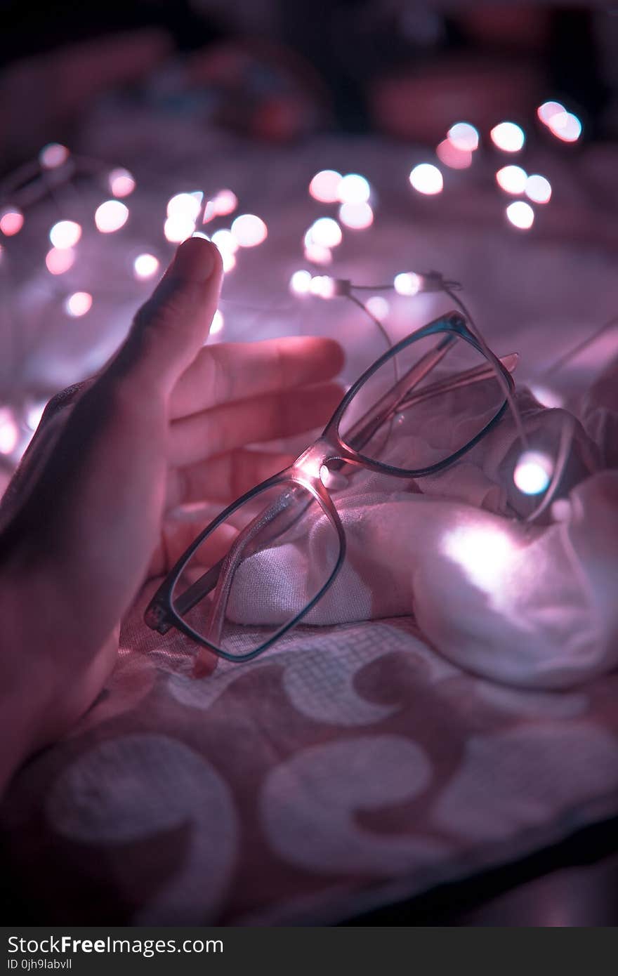 Black Frame Eyeglasses and White String Lights in White Textile