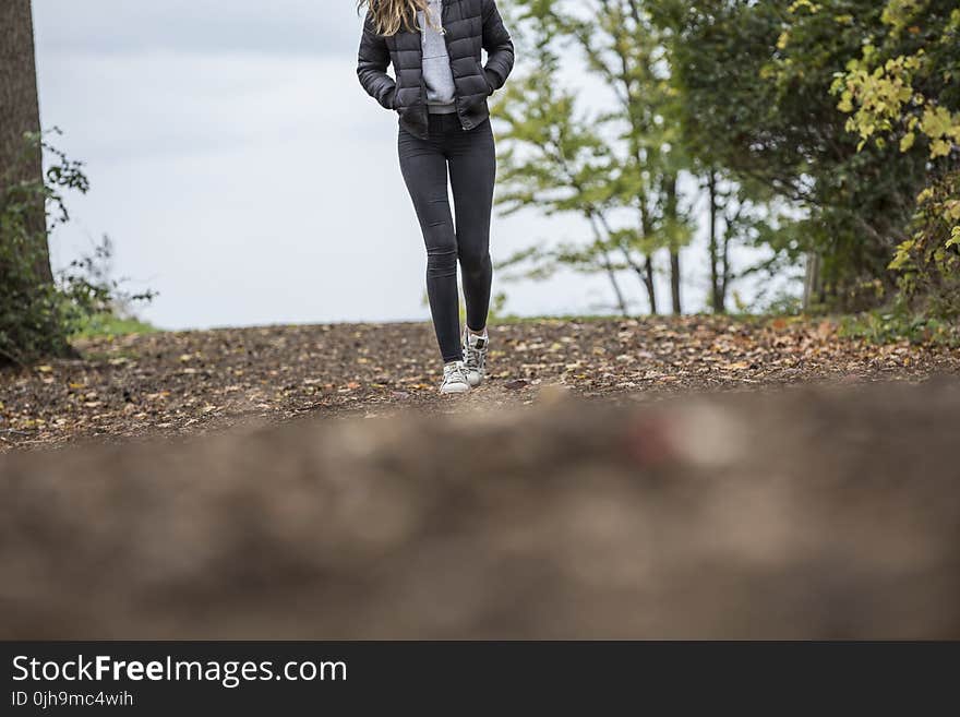 Woman in Black Leggings While Walking on Brown Road